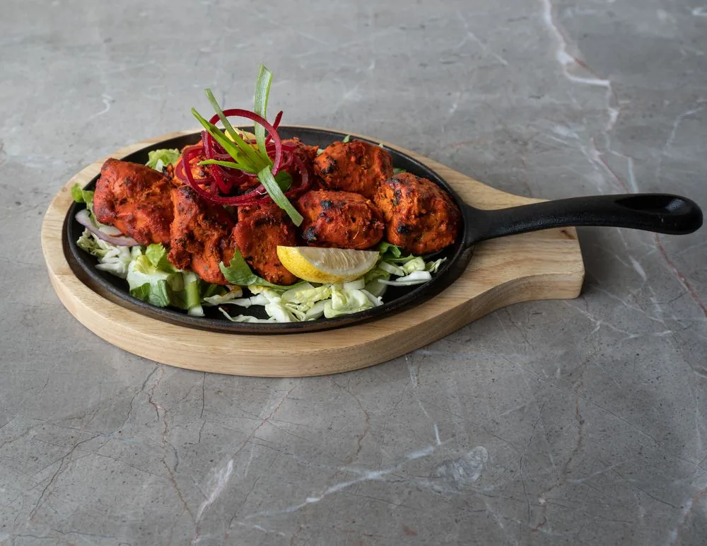 Sizzling tandoori chicken on a cast-iron platter